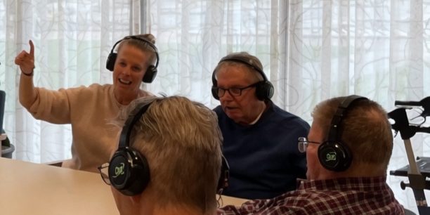 Residents with headphones at the table, one of them giving a thumbs up