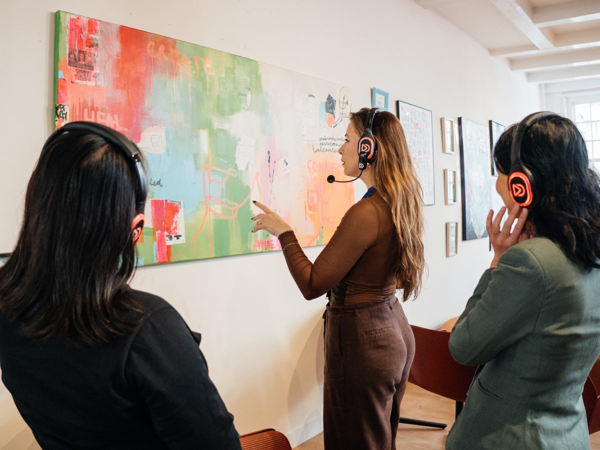Visitors with headphones in front of a painting