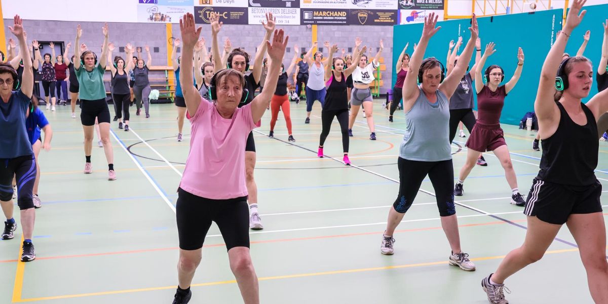Gruppass i en sporthall, deltagare med trådlösa hörlurar