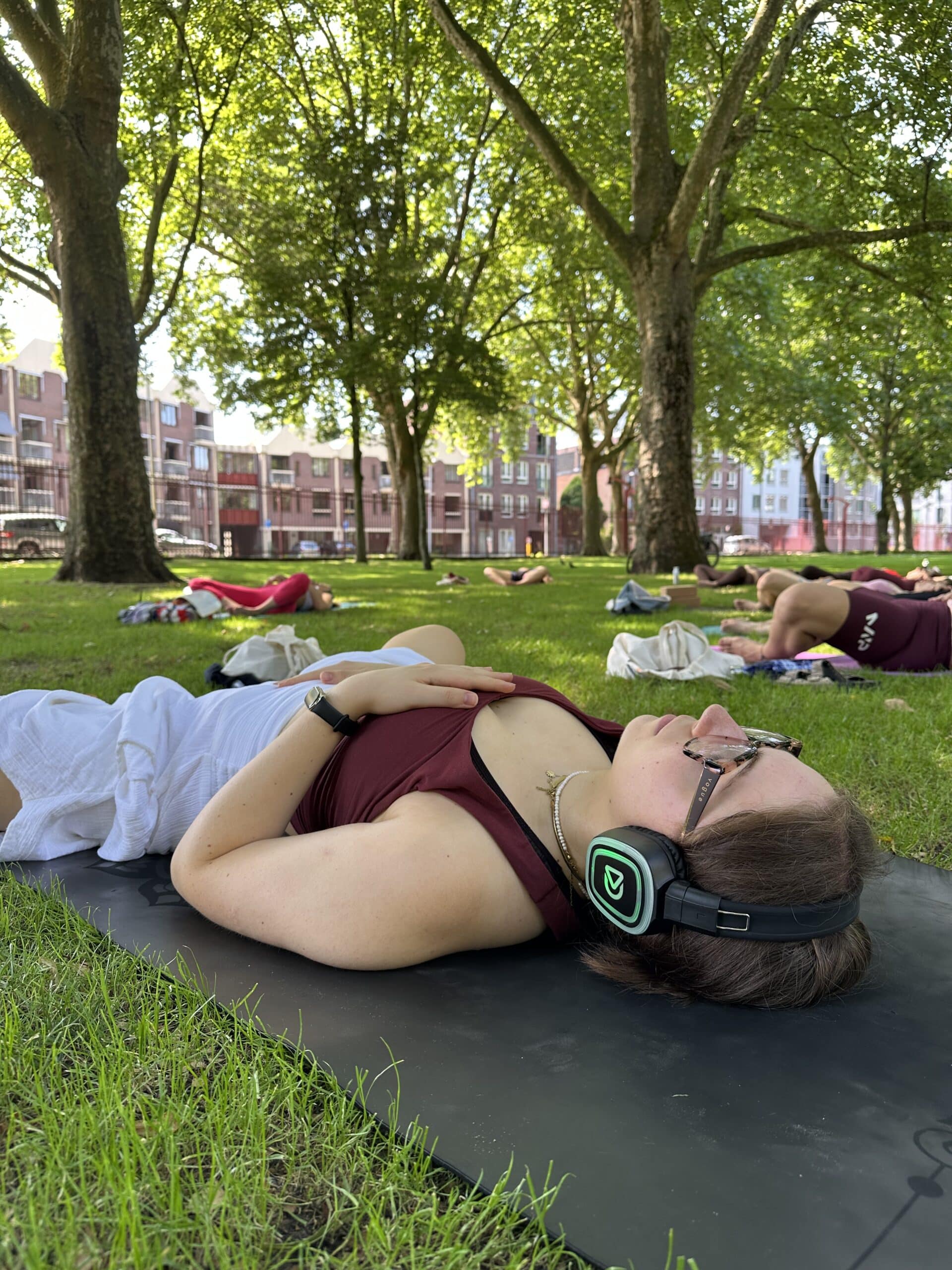 Clase de yoga en el parque con auriculares Dolly Digital
