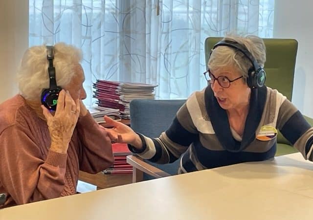Twee ouderen met een koptelefoon meezingend - muziekactiviteiten voor ouderen - Dolly Digital